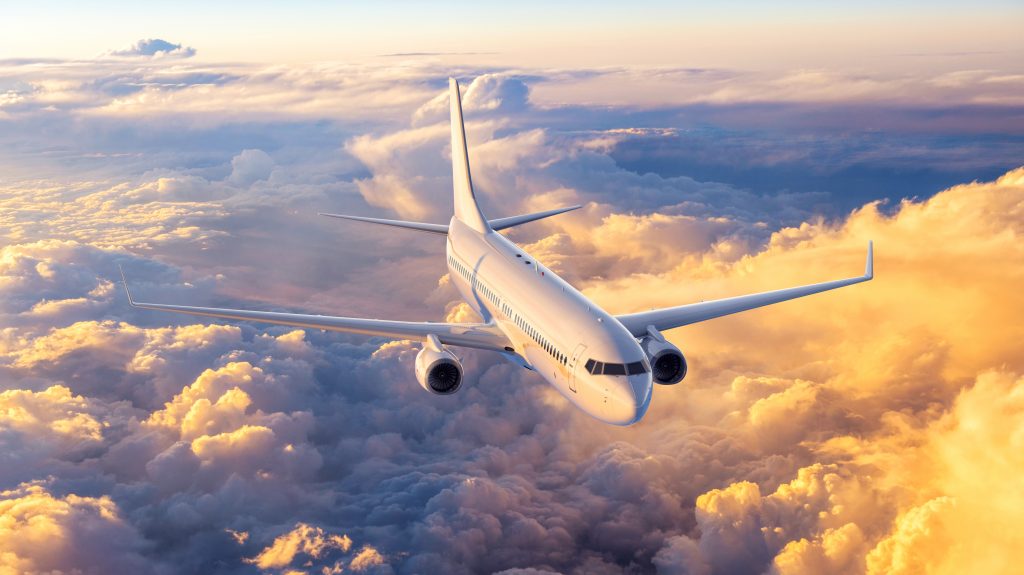 Over head view of silver airplane flying above the white puffy clouds 