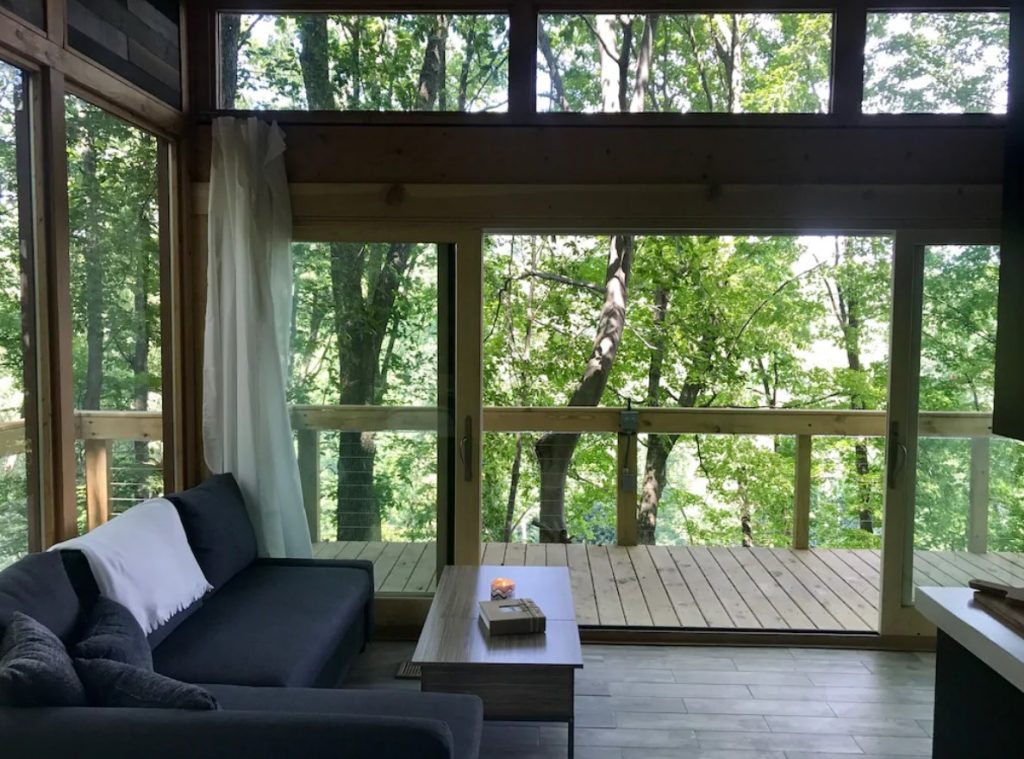 Inside a treehouse that has a large living area with floor to ceiling windows that look out onto the woods. One of the best places for glamping in Ohio. 