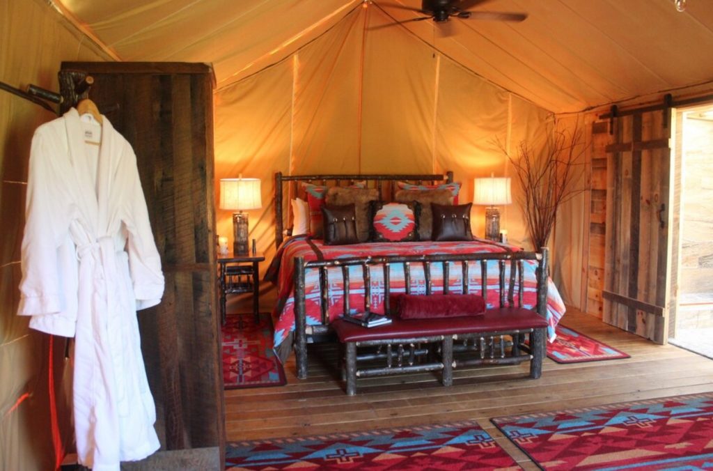 The interior of a glamping tent with a king-sized bed, southwestern style décor, and a private bathroom. One of the best places for glamping in Ohio. 
