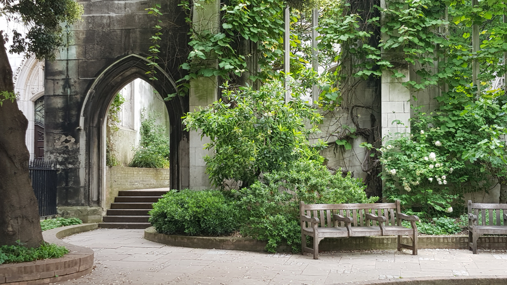 Pretty church garden with benches and plants growing on the walls.