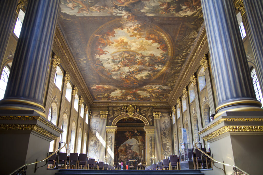 ornate painted ceiling decorated with gold w/several blue + white columns decorated with opulent gold touches.