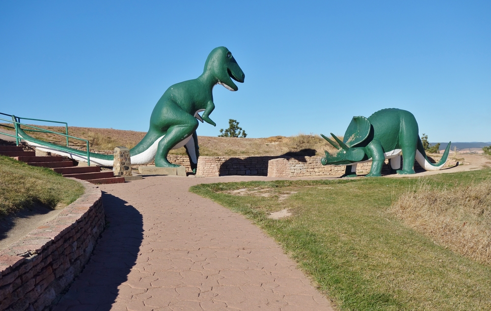 Two life-size dinosaurs at outdoor museum with stone walking path. attraction in Rapid City.