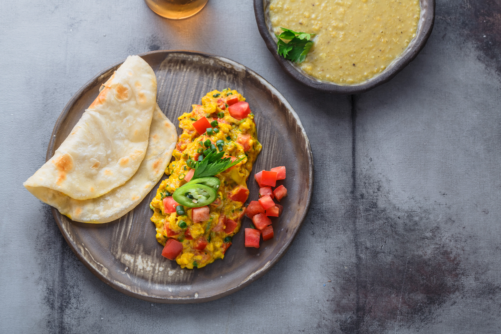 Akuri on a wooden plate with nann bread and a side of dahl. Dishoom serves one of the best breakfasts in London. 