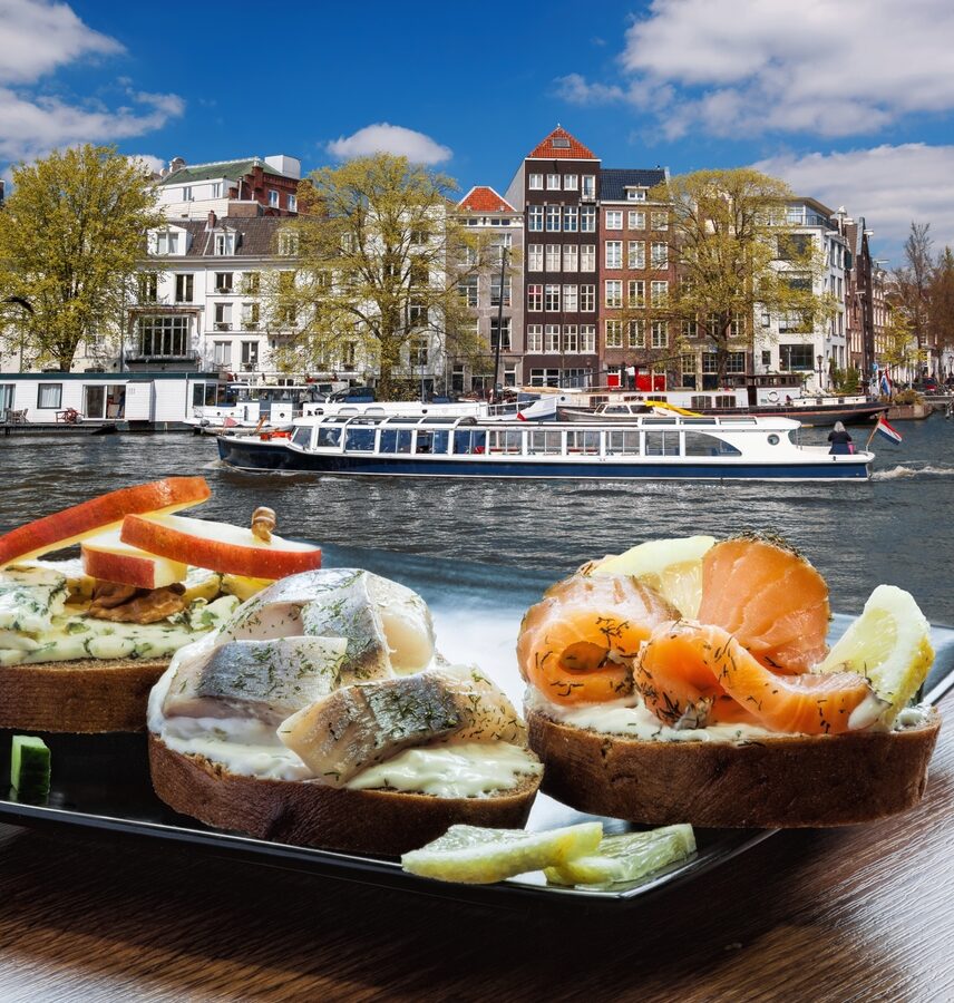 Breakfast in Amsterdam with view of canal and colorful buildings in background.