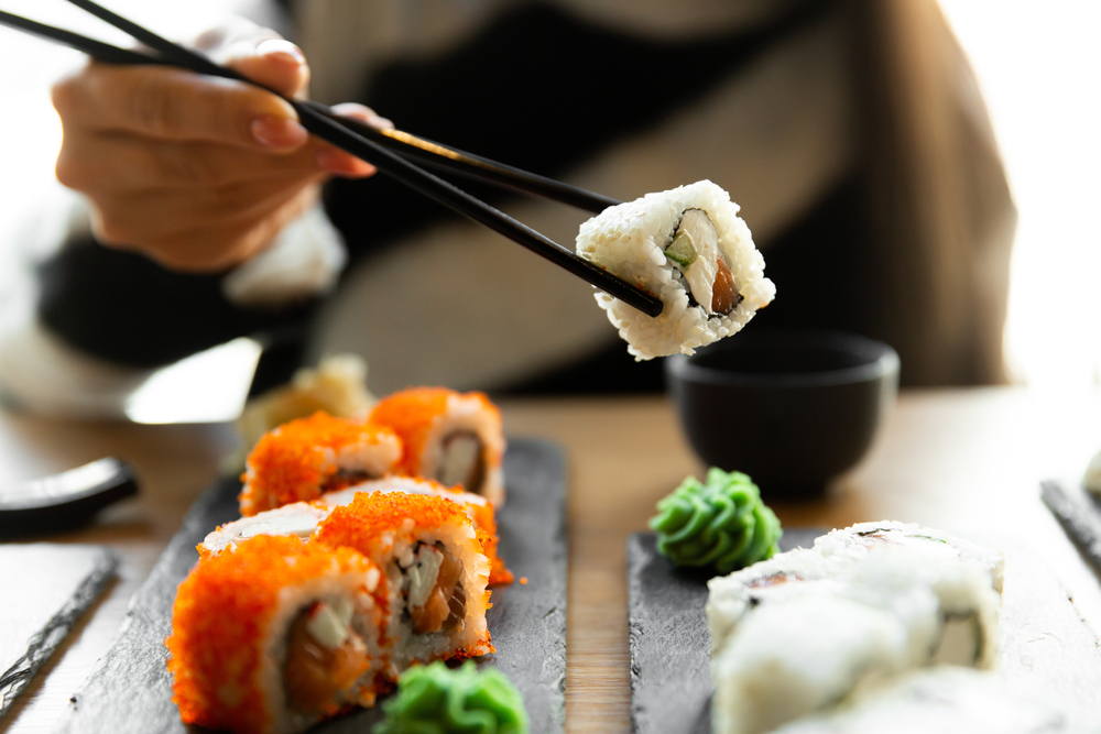  Woman eating sushi set with chopsticks on restaurant.