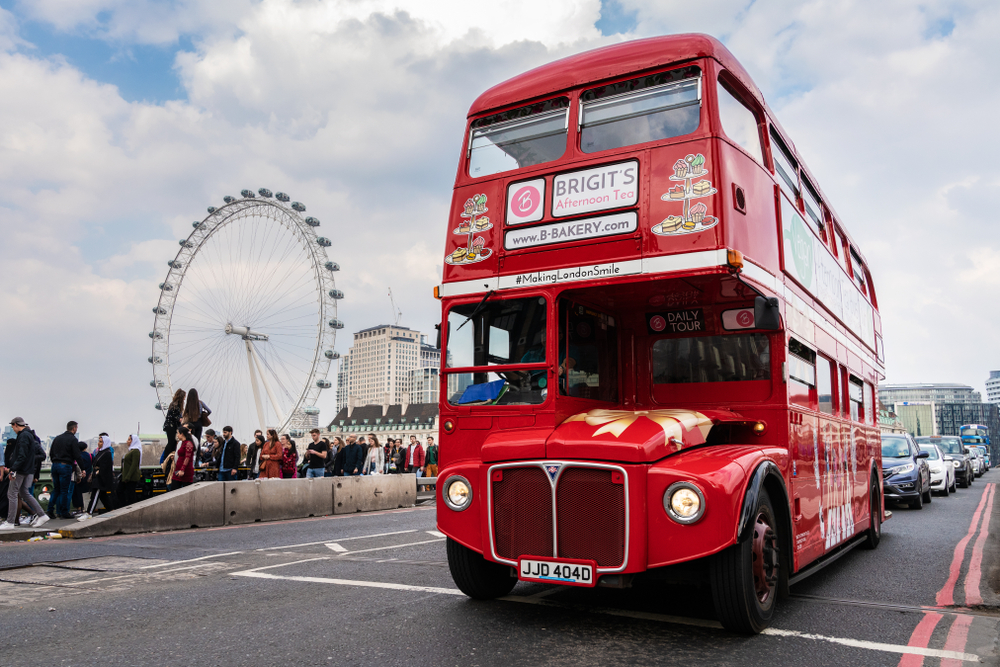 Tea in London served on a bus. This picture shows the bus going iver a bridhe with the London Eye in the background. 
