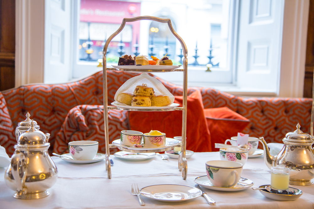 Afternoon Tea in London this picture shows a tepot cups and a cake stand on a table. 