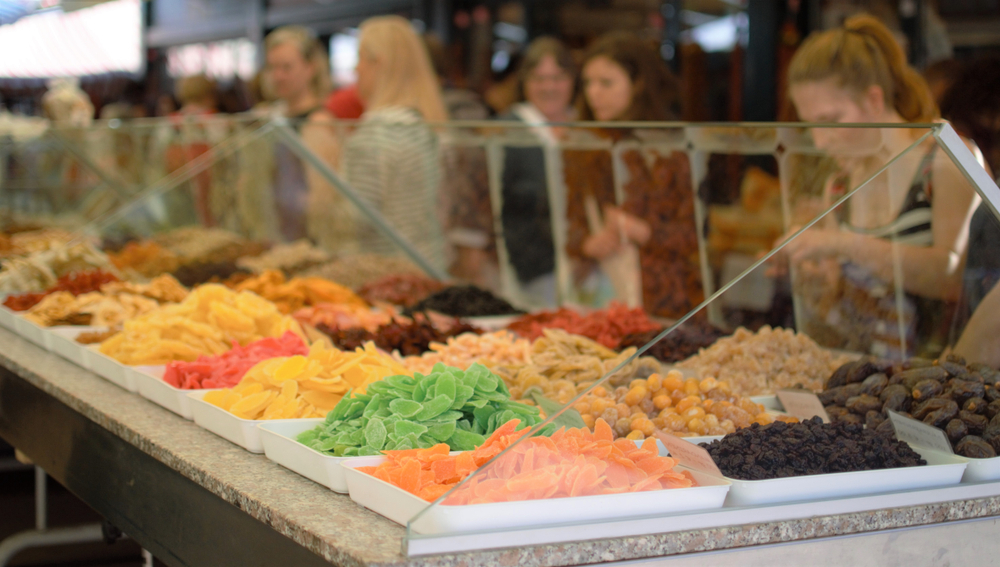 A vendor selling candy, nuts, and other goods at a market