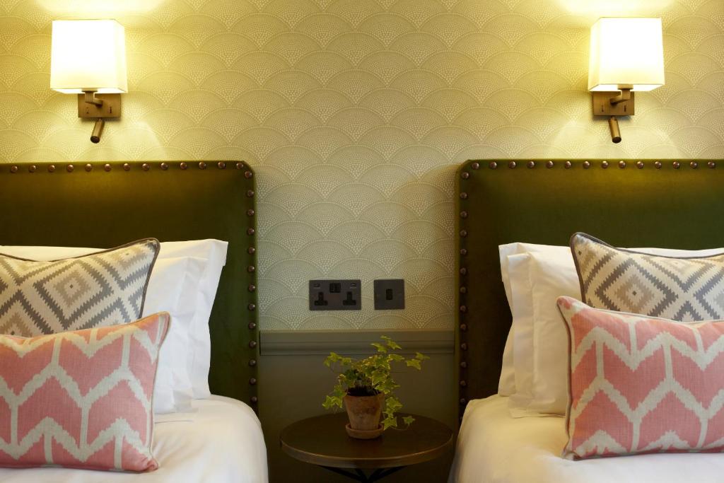 Picture of twin beds with green headboards and pink cushions in a hotel in London. 