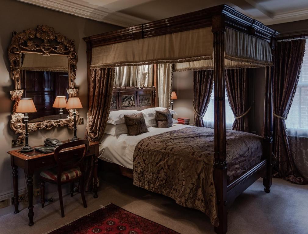 A gold and brown bedroom with a four poster bed a desk and gold mirror. The Rookery is one of the boutique hotels in London. 