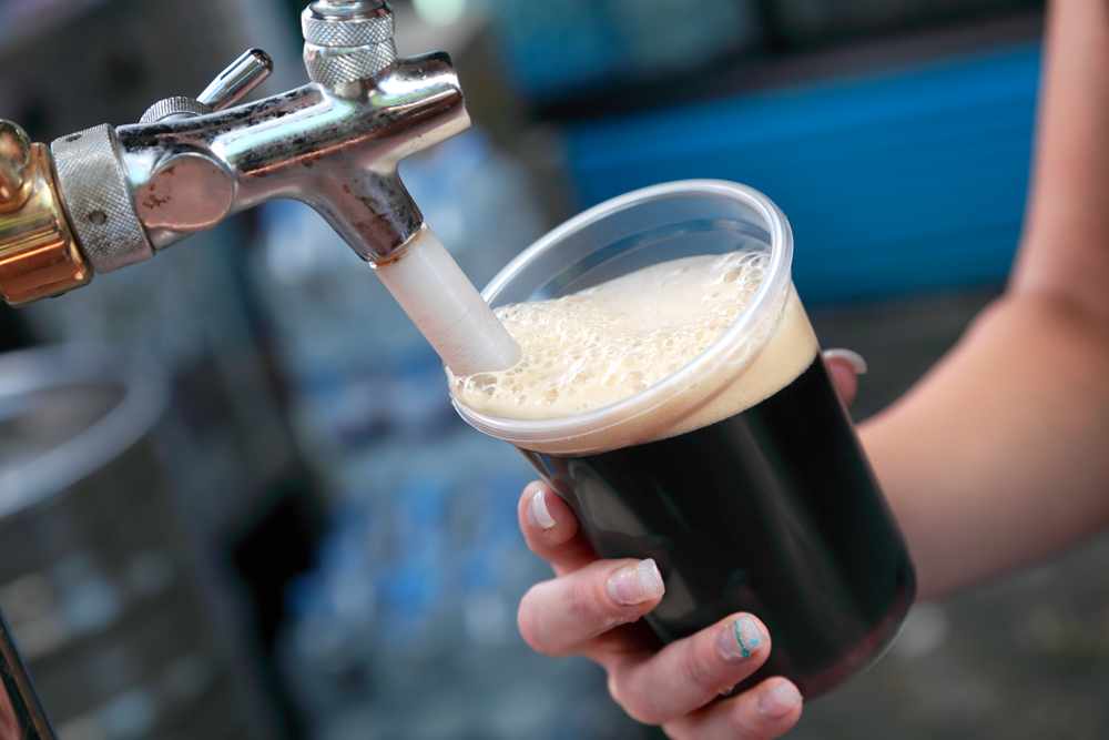 A person with long fingernails puring a pint of Guinness