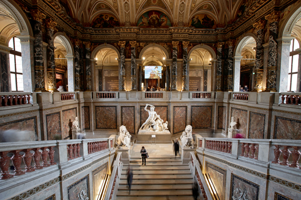 The staircase at the Kunsthistorisches Museum in Vienna. It is elaborately decorated and has marble sculptures. Its one of the best things to do in Vienna