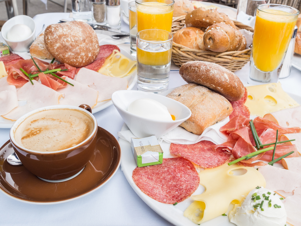 Cheese and meat breakfast on a table with orange juice and coffee. 