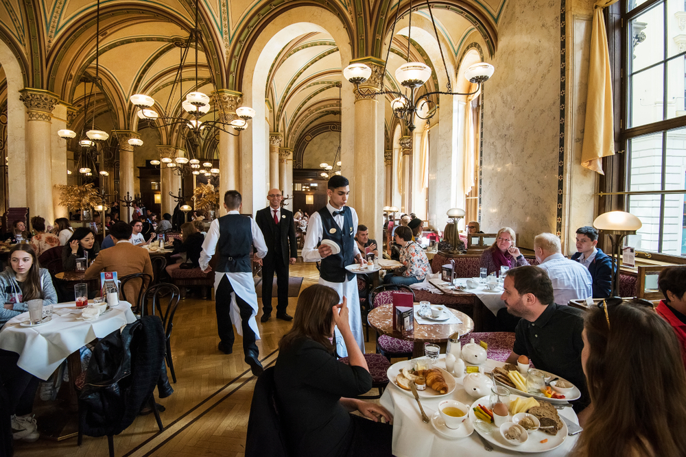 Interior of the Café Central. Café Central is a traditional Viennese café. People are at the tables in an article about restaurnats in Vienna. 