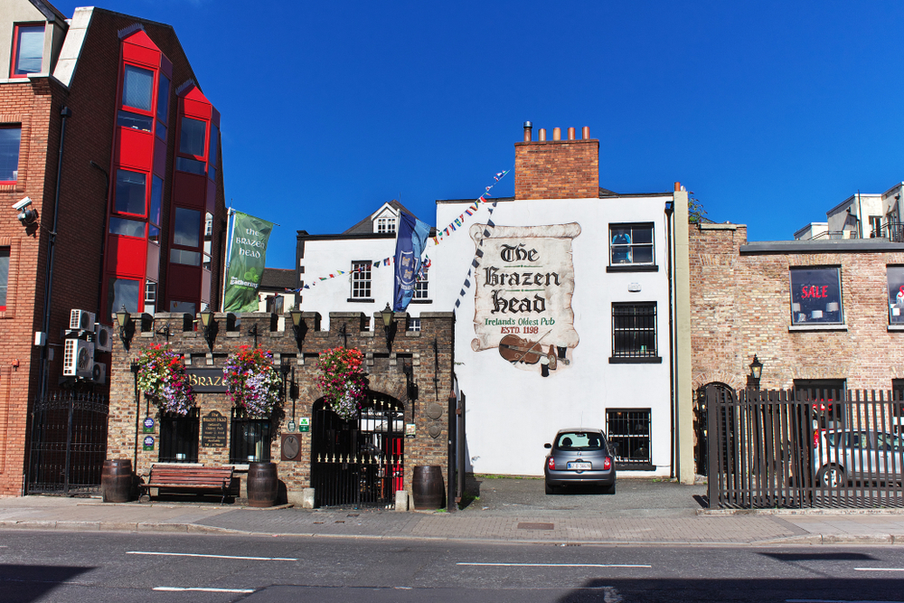 The outside of The Brazen Head, one of the oldest pubs in Dublin. It has a white painted exterior and an entrance that looks like part of an old castle