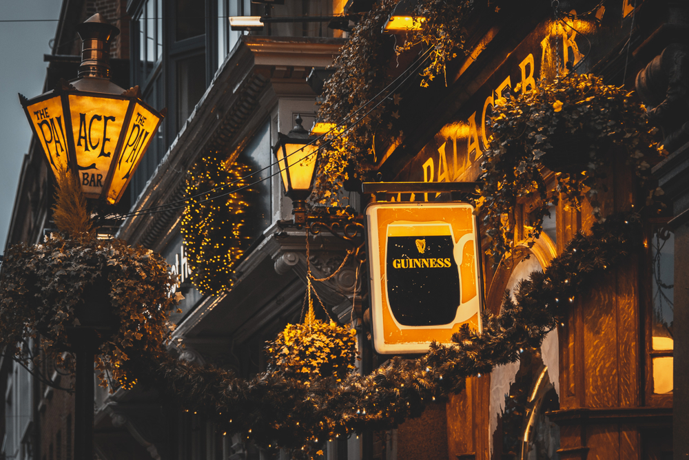 The front of The Palace Bar at night with it all lit up and a sign advertising Guinness, one of the best pubs in Dublin