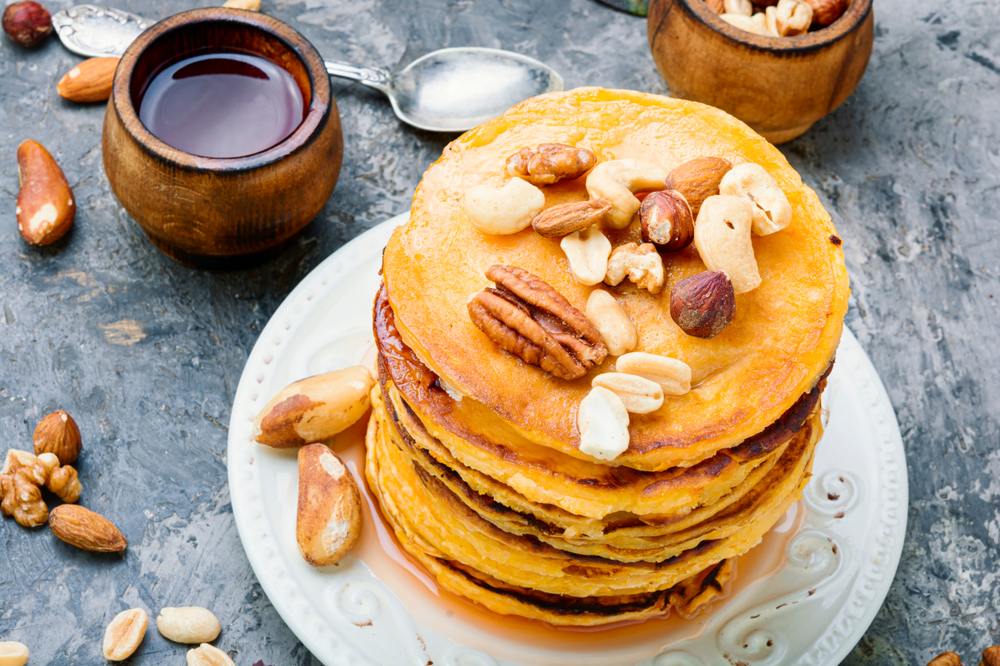 Appetizing pancakes with nuts and maple syrup. 