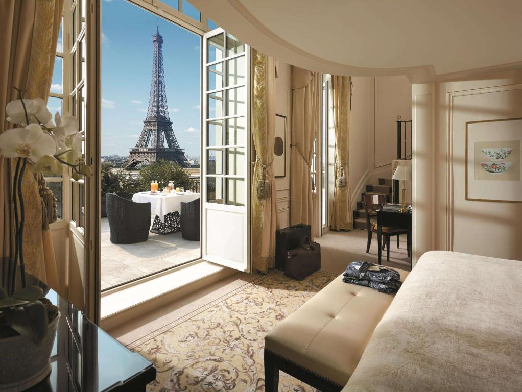 Luxury boutique hotel in Paris with a balcony overlooking the Effiel Tower. The room has large windows drapped in gold fabric.   