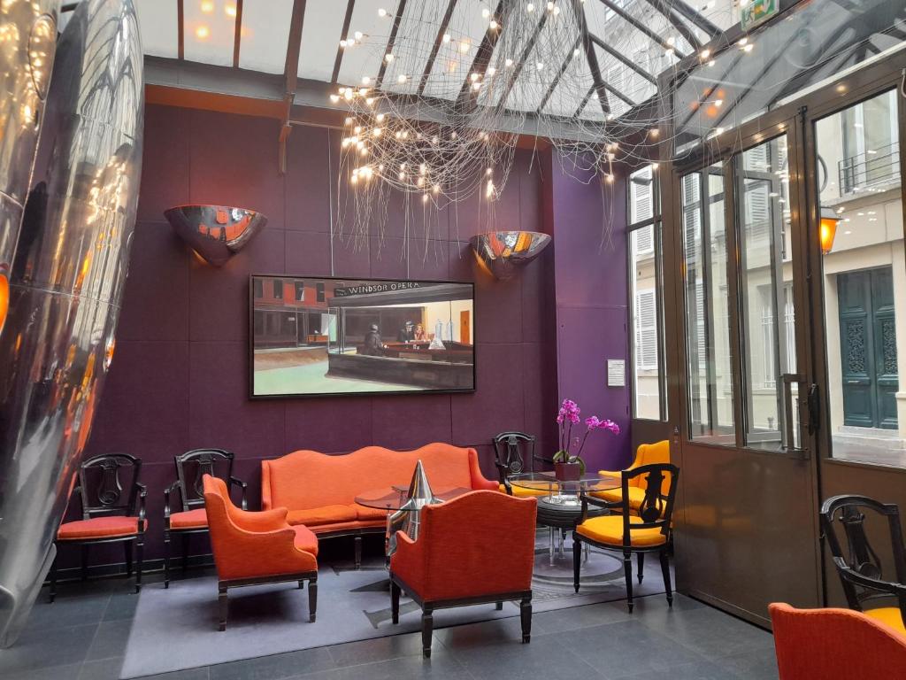 A beautiful lobby with aubergine walls and orange chairs. 