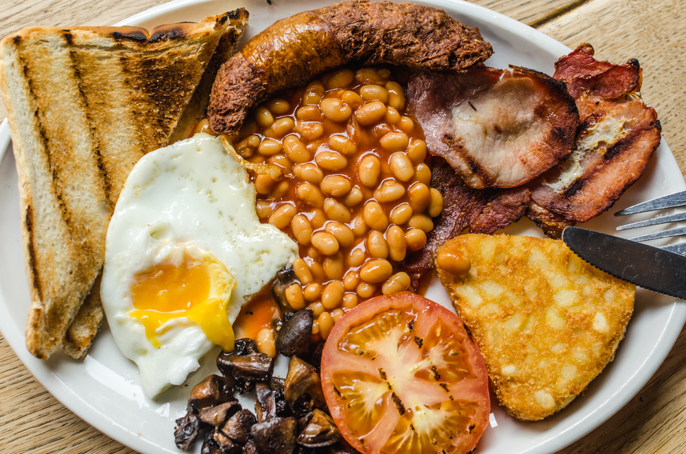 A large plate with eggs, toast, beans, sausage, ham, tomatoes, mushrooms, and a hash brown that you can find for breakfast in Dublin