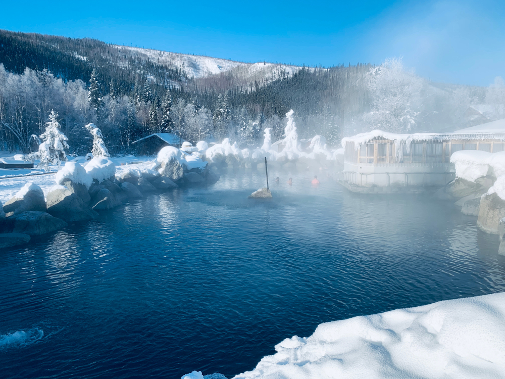 The steaming outdoor hot spring lake surrounded by snow at Chena Hot Springs, one of the best places to visit in Alaska.