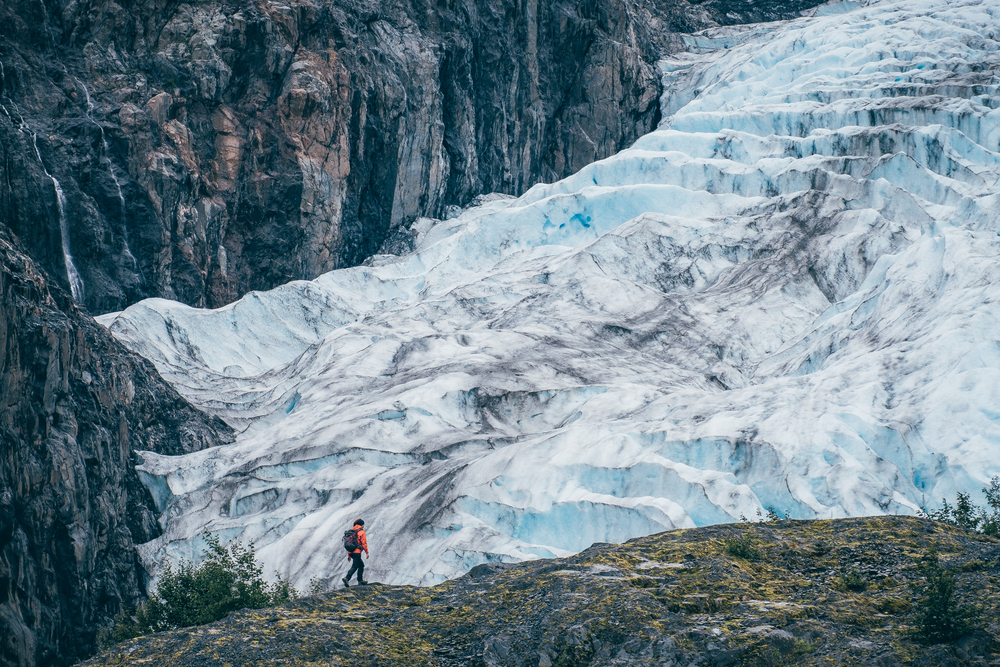 Hiker walks along a ridge overlooking the epic Exit Glacier, one of the best places to visit in Alaska.