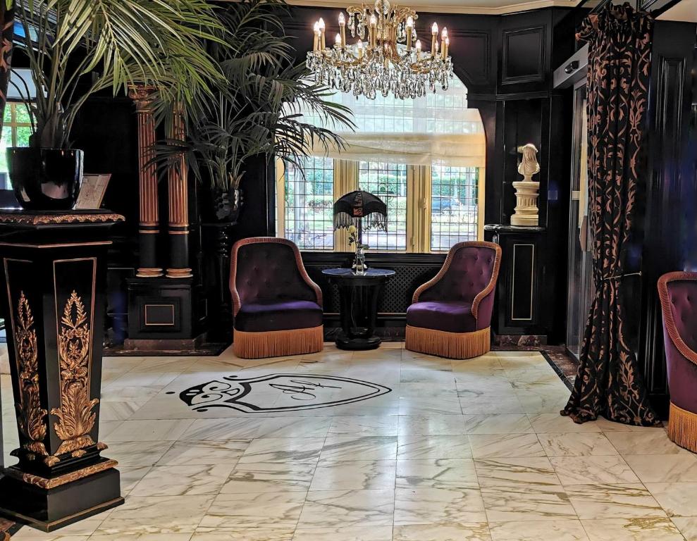 An opulently decorated room with marble floors, velvet chairs, a chandelier, and black walls and curtains