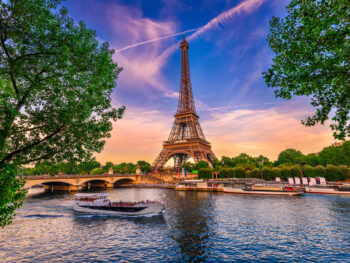 eiffel tower in the evening with boats cruising in seine river