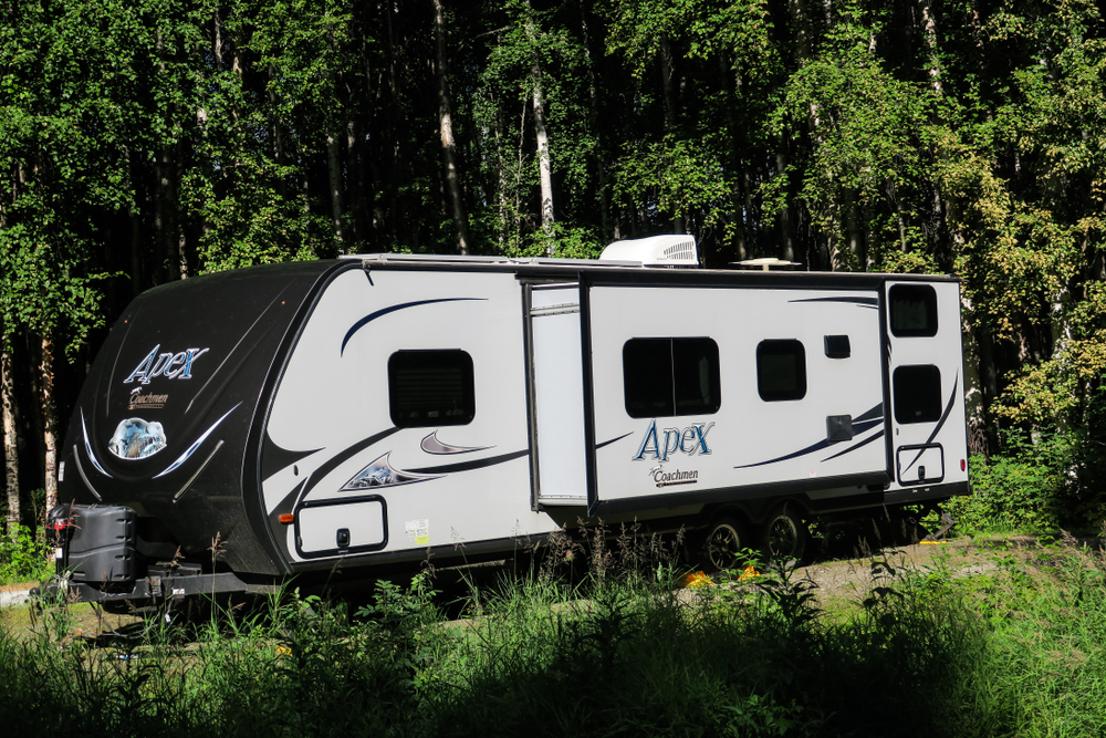 RV surrounded by trees in an article about camping in Alaska. 