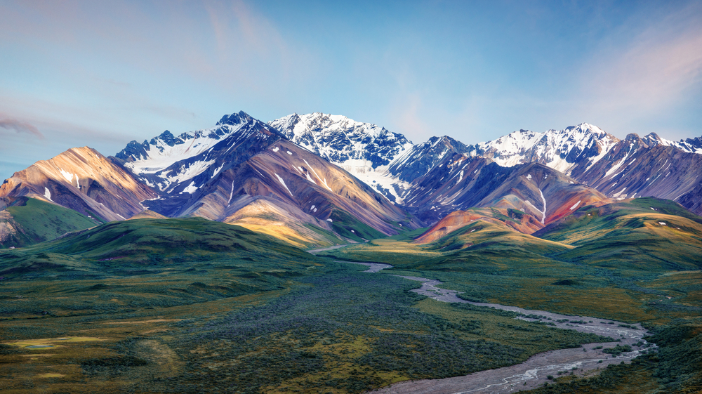 Alaska Denali National Park the picture show a valley with a river running through and the mountains beyond. 