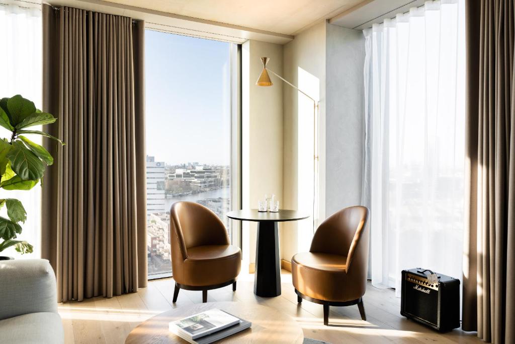A simple and modern room with floor-to-ceiling windows that look out onto the city at one of the best boutique hotels in Amsterdam