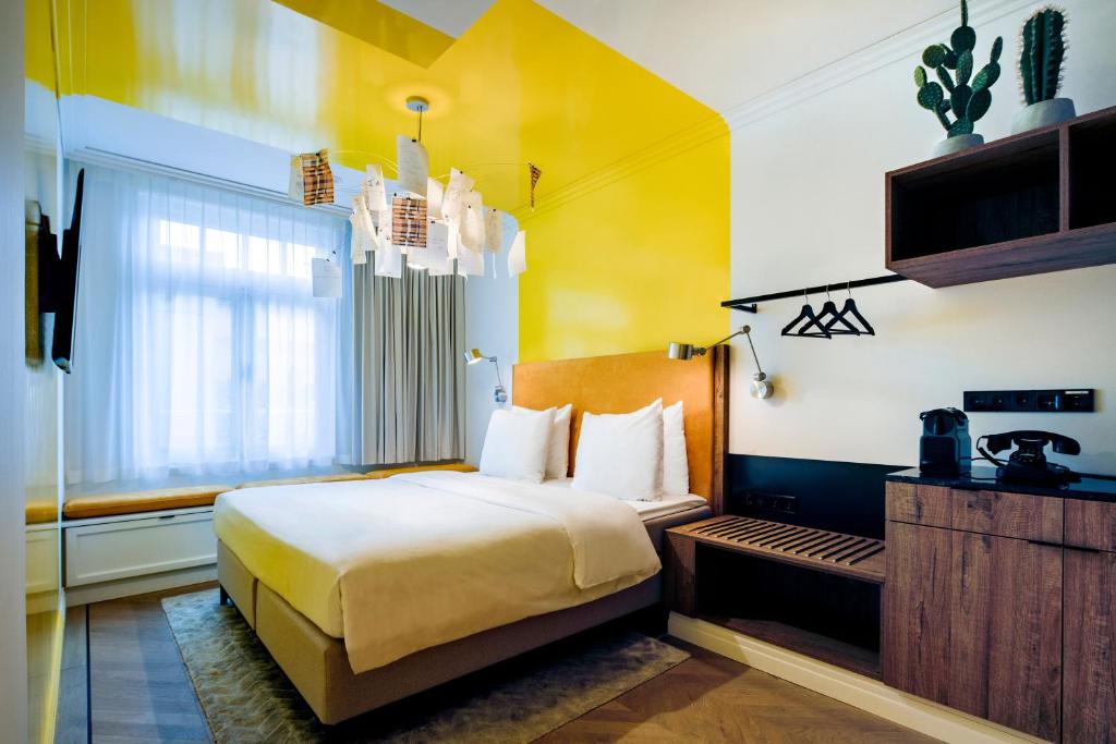 A bright room in a boutique hotel in Amsterdam that has a large yellow stripe painted from the wall to the ceiling behind the bed