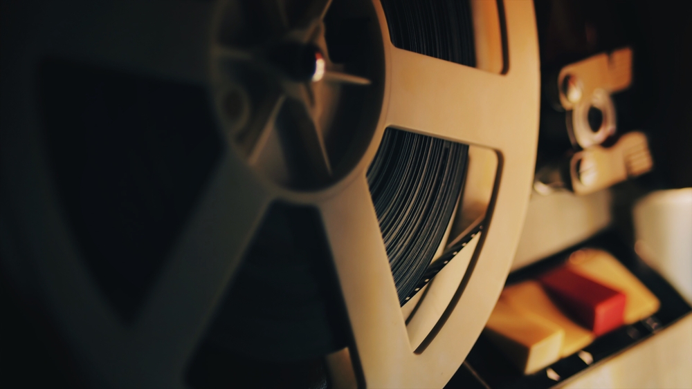 Old 8mm film projector playing in the night. Close-up of a reel with a film.