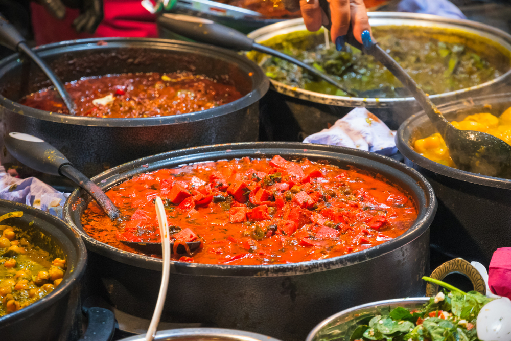 A variety of curries hot food on display at Brick Lane. Having a curry is one of the things to do in Shoreditch. 