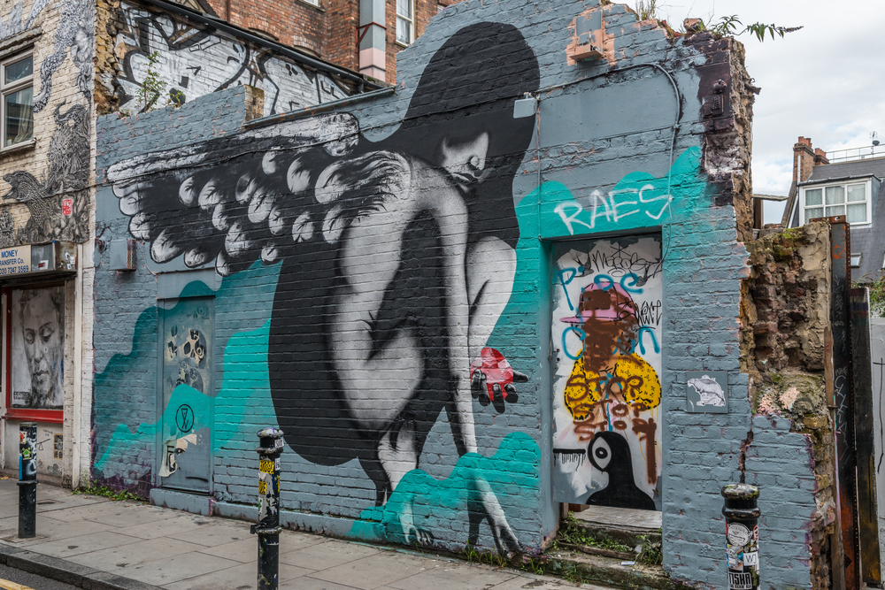large painting of female with wings on green building. things to do in Shoreditch