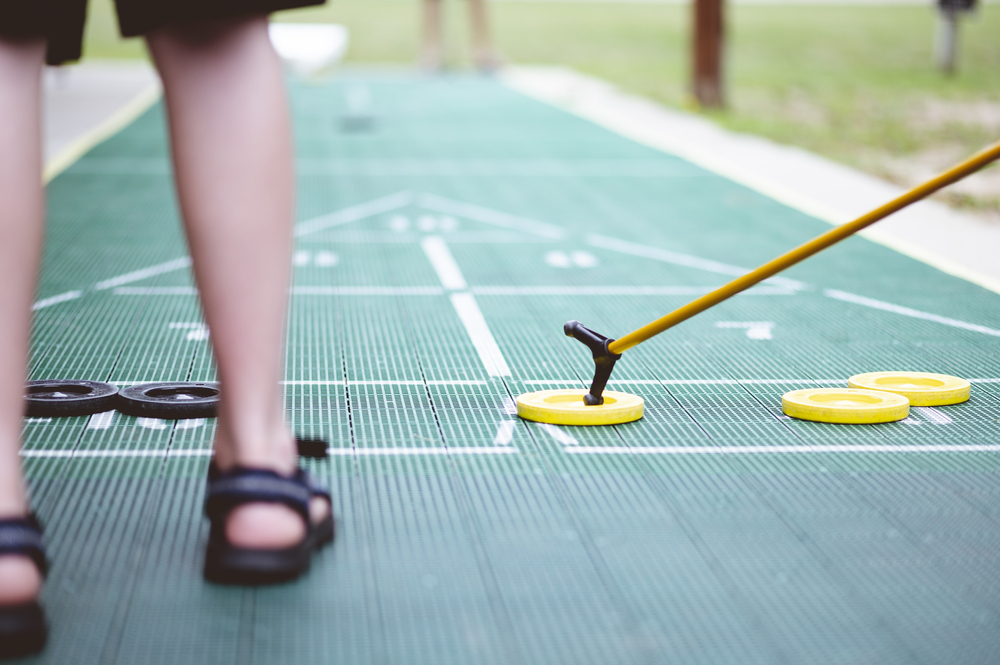 A selective focus shot of shuffleboard game. Two people are playing.  