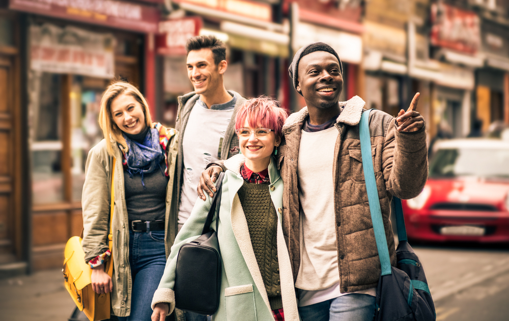 Happy multiracial friends walking on Brick Lane. The article is about things to do in Shoreditch. 