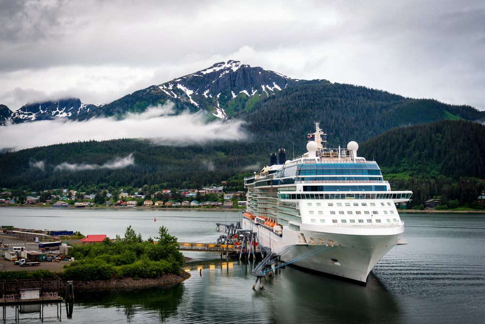 A cruise ship at a port with cloudy mountains in the background in Alaska in May.