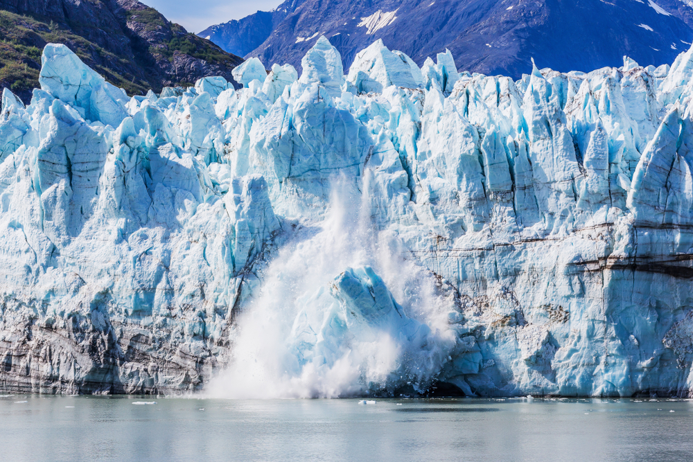A chuck of ice calving off of the tall side of Margerie Glacier in Alaska.