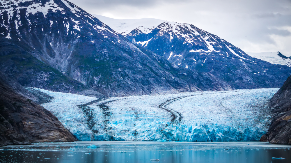 Beautiful, blue North Sawyer Glacier in Alaska with mountains over it.