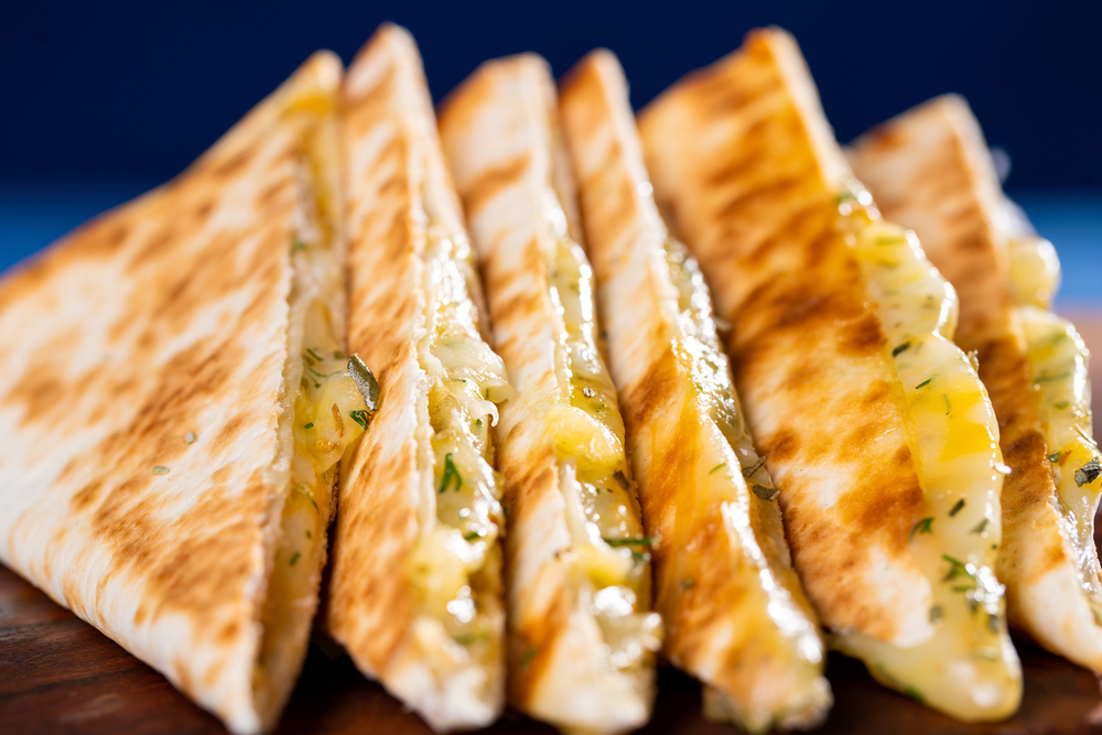 Cheese quesadilla on wooden board with a blue background. The article si about the best restaurnats in Covent Garden. 