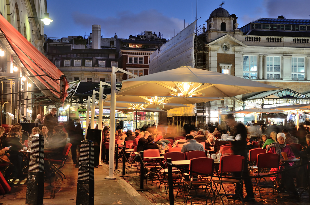 People sitting in an outside cafe at night. The article is about the best restaurants in Covent Garden 