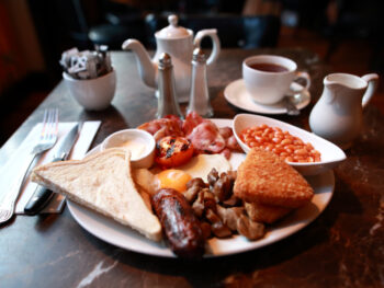 a plate with eggs, bacon, toast, beans, and sausages breakfast in covent garden