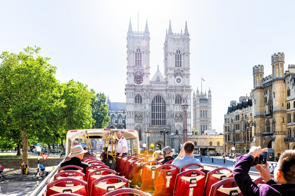 Point of view pov riding Big Bus guided tour in London summer chairs seats view of Westminster Abbey church building.