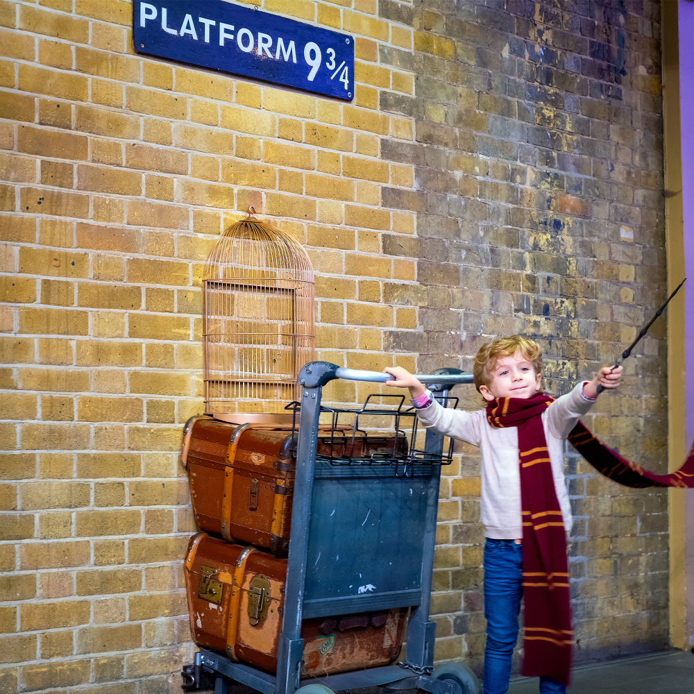 Child poses at the platform 9 3/4 that taken fron Harry Potter movie in King's Cross station. This is one of the things to do in London with kids. 