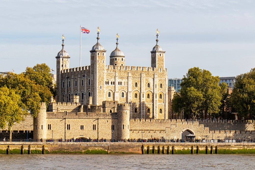 A view of The Tower Of Ldondon acrosss the water. The union jack is flying.  