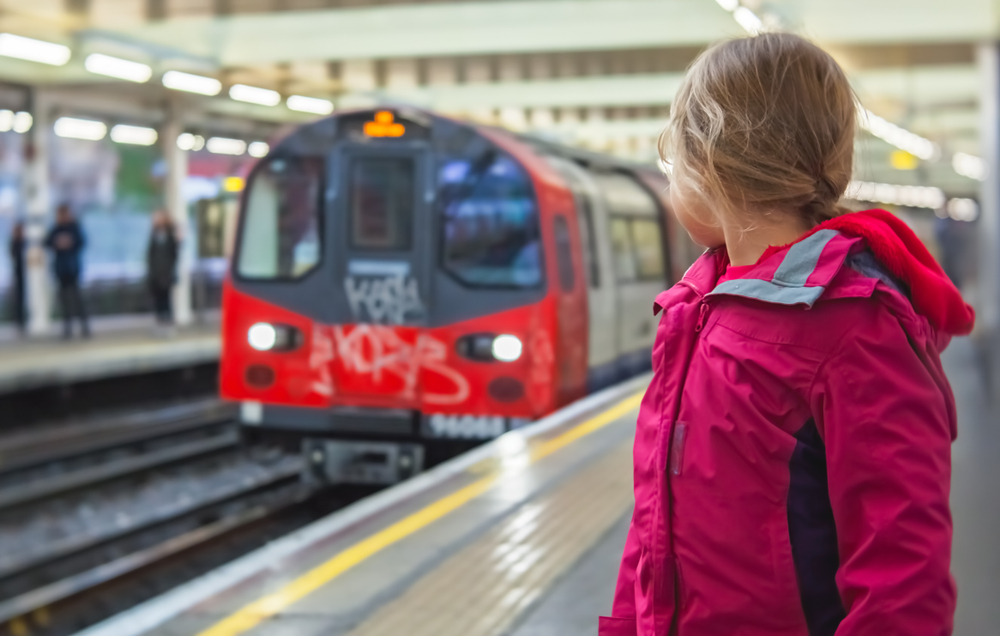 Little girl standing on the platform and watching the approaching underground train 