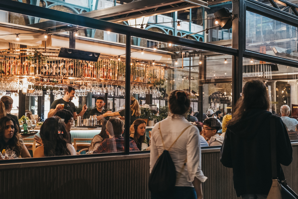 Women walking past the windows of Buns and Buns restaurant in Covent Garden Market. 