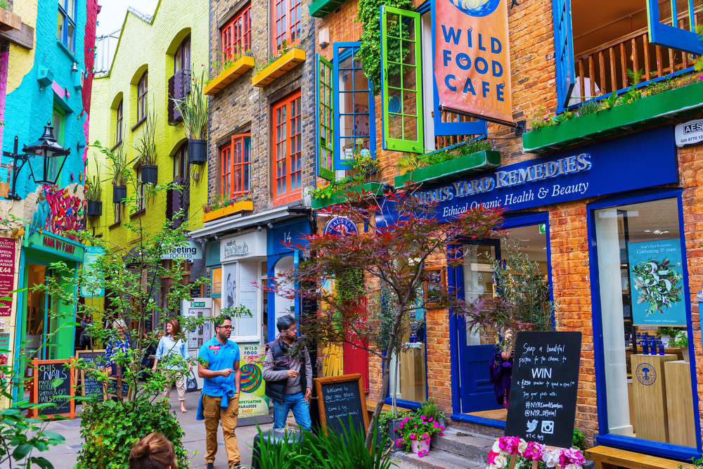 Neals Yard with unidentifed people. It is a small alley in Covent Garden with colorful houses. It contains several health food cafes and values driven retailers