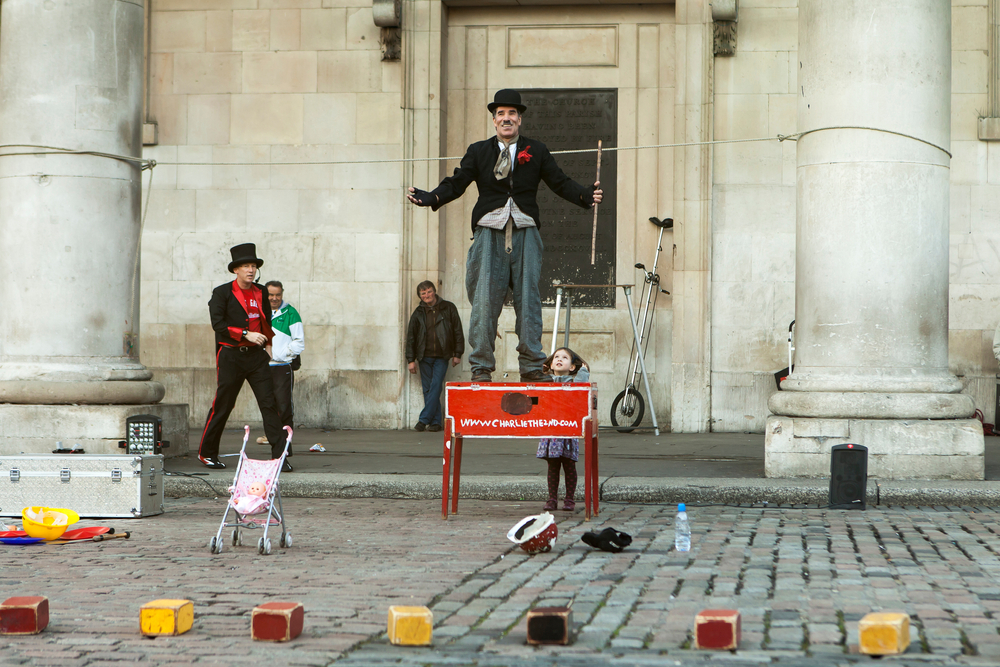 Actor disguised as Charlie Chaplin shows a performance in the main square of Covent Garden under the church